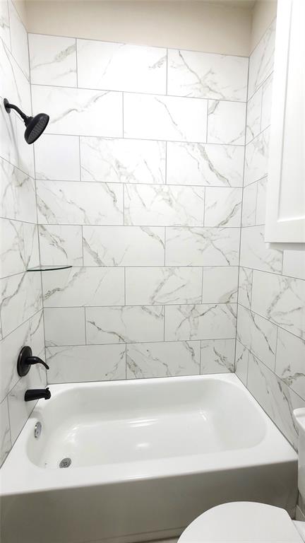 bathroom featuring tiled shower / bath and toilet