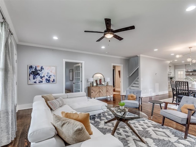 living room with ceiling fan with notable chandelier, dark hardwood / wood-style flooring, and ornamental molding