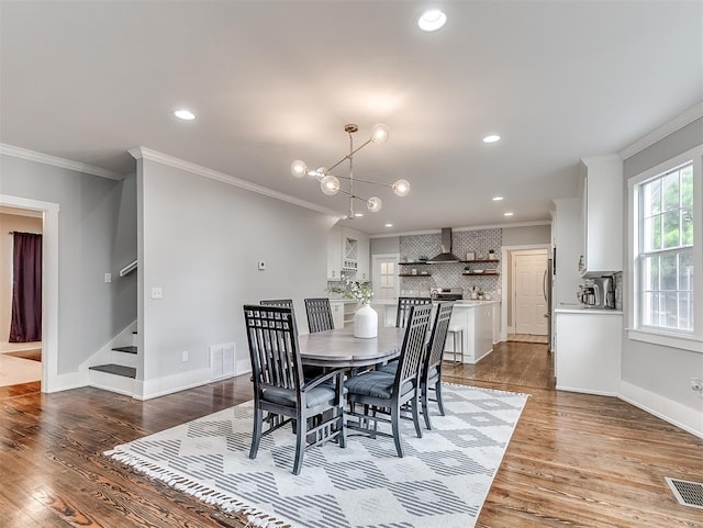 dining room featuring light hardwood / wood-style floors, ornamental molding, and a chandelier