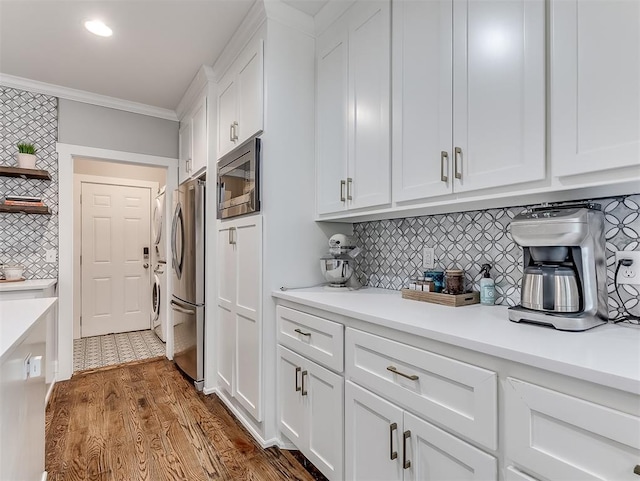 kitchen featuring backsplash, hardwood / wood-style floors, white cabinets, and stainless steel appliances