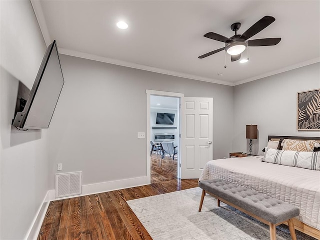 bedroom featuring ceiling fan, ornamental molding, and dark wood-type flooring