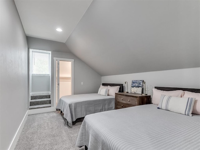 carpeted bedroom featuring a spacious closet and vaulted ceiling