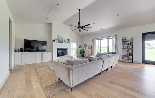 living room featuring light wood-type flooring, high vaulted ceiling, ceiling fan, and a healthy amount of sunlight