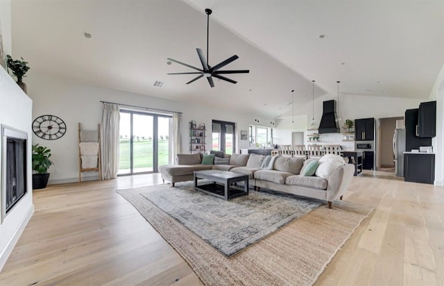 living room featuring high vaulted ceiling, light hardwood / wood-style flooring, and plenty of natural light