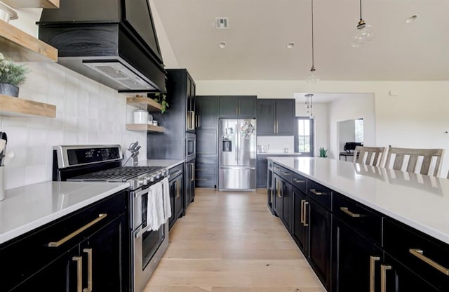 kitchen featuring hanging light fixtures, stainless steel appliances, a kitchen breakfast bar, backsplash, and light hardwood / wood-style floors