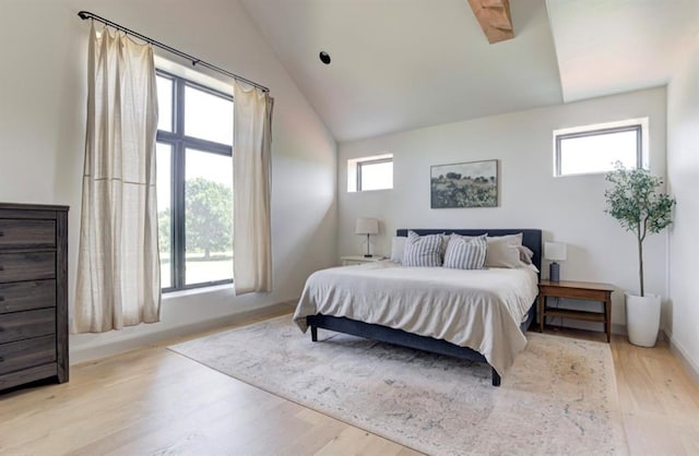 bedroom featuring light hardwood / wood-style flooring, vaulted ceiling, and multiple windows