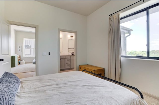 bedroom featuring ensuite bathroom and light colored carpet