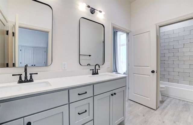 full bathroom featuring toilet, hardwood / wood-style floors, vanity, and tiled shower / bath combo