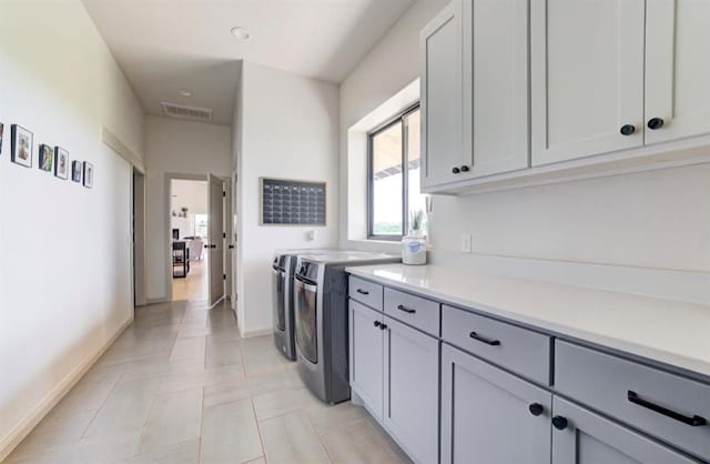 laundry room with light tile patterned flooring, cabinets, and independent washer and dryer