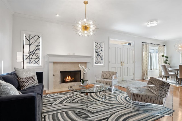 living room with a chandelier, ornamental molding, a fireplace, and light hardwood / wood-style flooring