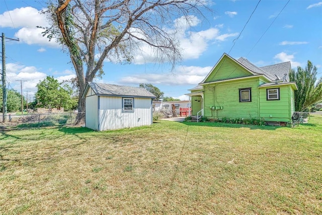 rear view of house with a storage unit and a yard