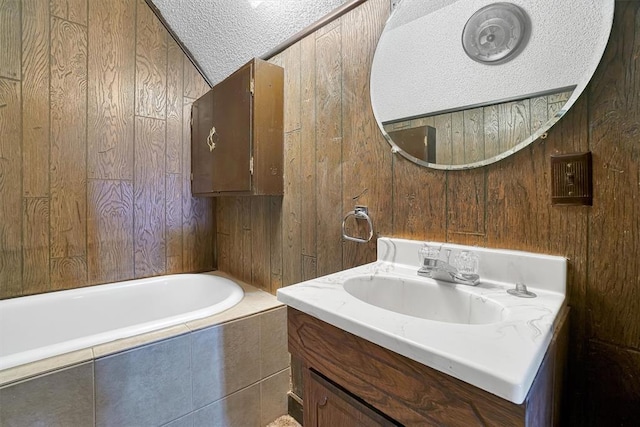 bathroom featuring wooden walls, vanity, a bath, and a textured ceiling