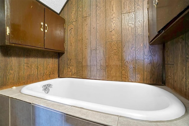 bathroom with wooden walls and a relaxing tiled tub