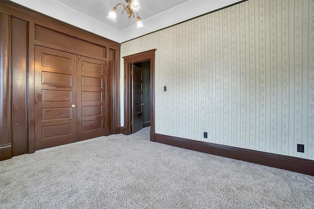 unfurnished bedroom featuring carpet floors, a textured ceiling, and an inviting chandelier