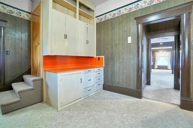 interior space with light carpet and wooden walls