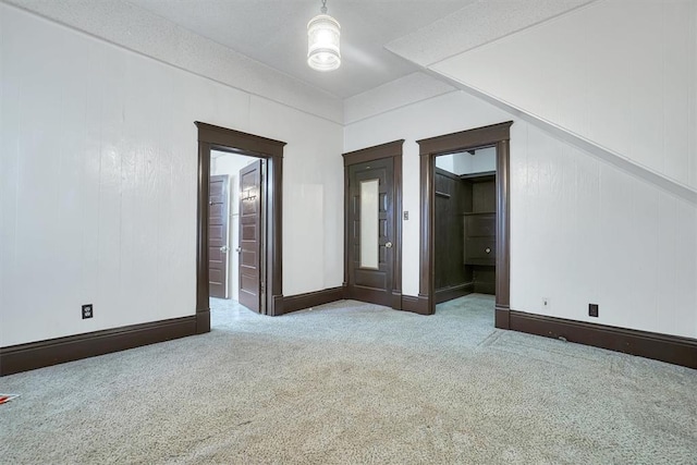 carpeted spare room featuring wood walls