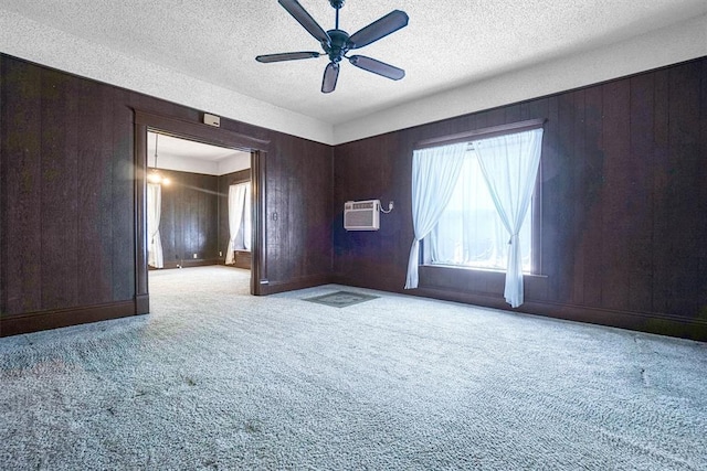 carpeted empty room featuring a textured ceiling, ceiling fan, and wood walls