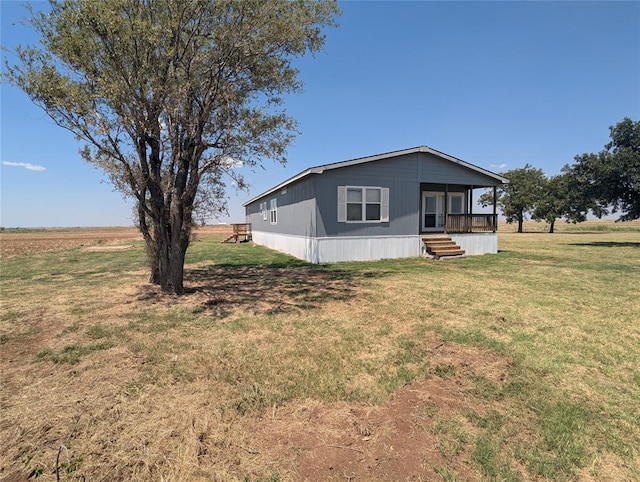 view of side of home with a lawn and a rural view