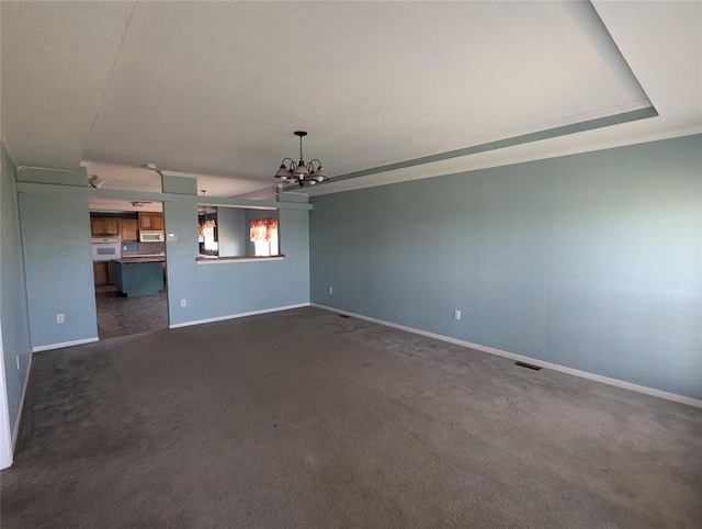 unfurnished living room with dark carpet, crown molding, a tray ceiling, and an inviting chandelier