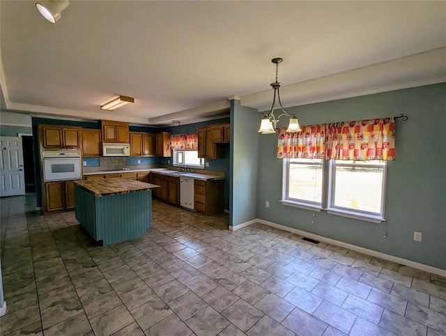 kitchen with white appliances, a center island, hanging light fixtures, and a notable chandelier