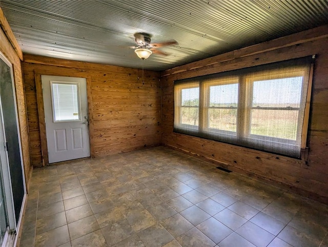 spare room featuring a wealth of natural light, wooden walls, and ceiling fan