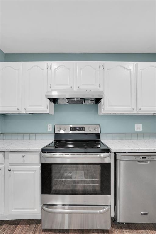 1033 Coe St, Altus, OK 73521 - kitchen with appliances with stainless steel finishes, ventilation hood, light countertops, and white cabinetry