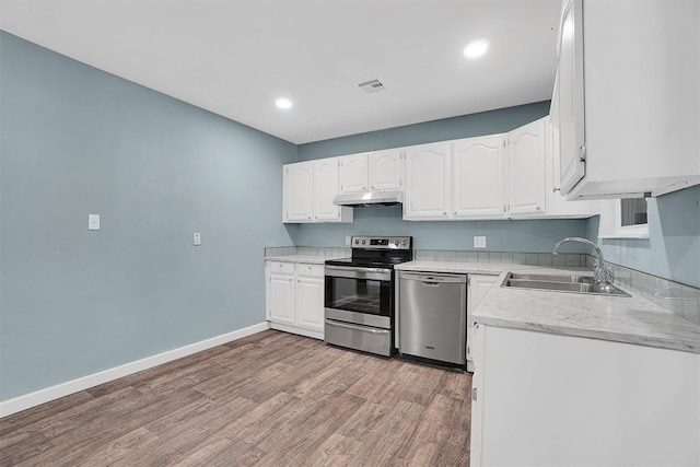 1033 Coe St, Altus, OK 73521 - kitchen with appliances with stainless steel finishes, a sink, light wood-style floors, white cabinetry, and light countertops