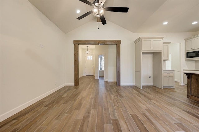 unfurnished living room with ceiling fan, light hardwood / wood-style floors, and vaulted ceiling