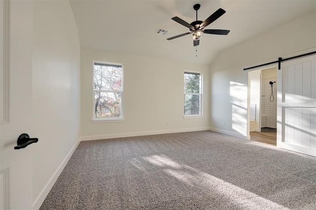 interior space with carpet flooring, ceiling fan, a barn door, and multiple windows