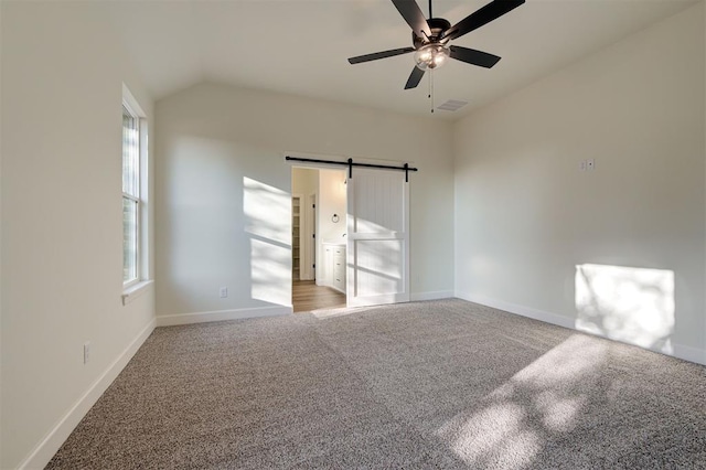 spare room featuring ceiling fan, a barn door, and carpet floors