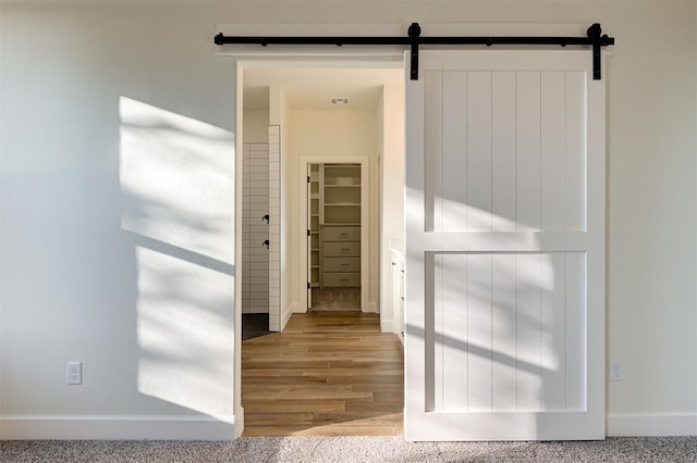 hall featuring a barn door and light hardwood / wood-style floors