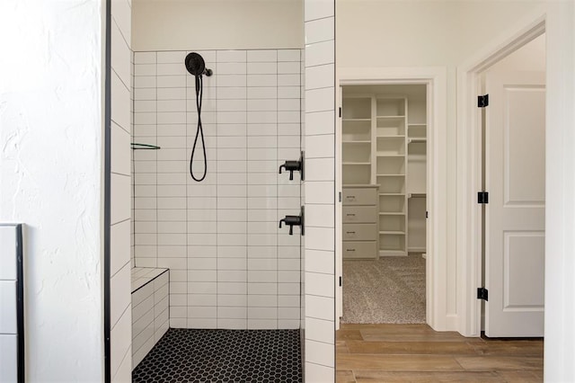 bathroom with tiled shower and hardwood / wood-style flooring