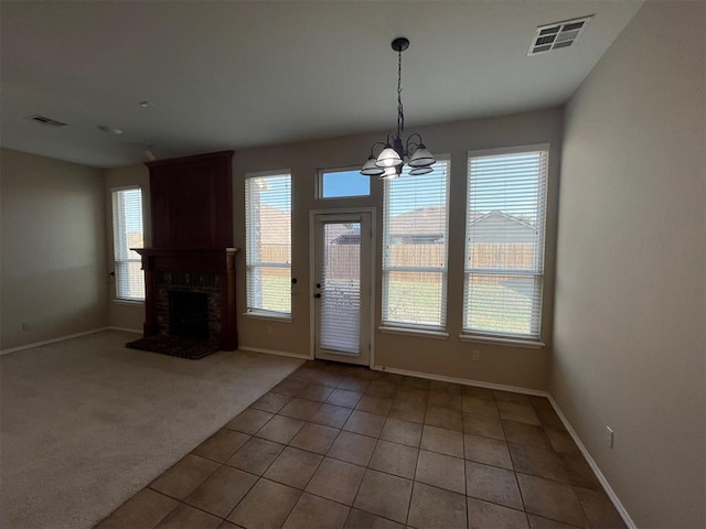 carpeted entrance foyer with a healthy amount of sunlight, a fireplace, and an inviting chandelier