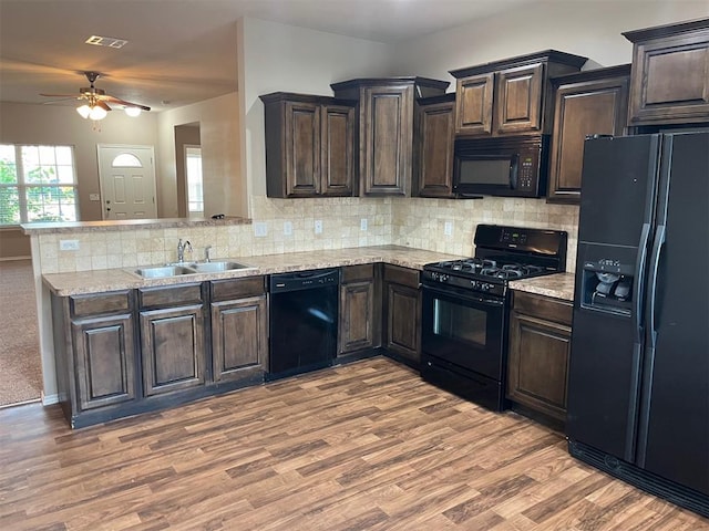 kitchen with tasteful backsplash, dark brown cabinets, sink, black appliances, and hardwood / wood-style flooring