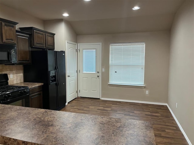 kitchen featuring tasteful backsplash, dark brown cabinetry, black appliances, dark hardwood / wood-style floors, and lofted ceiling