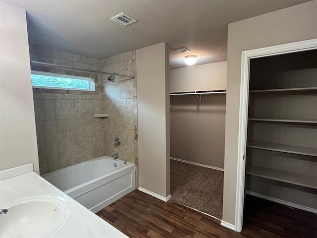 bathroom with hardwood / wood-style floors, tiled shower / bath combo, and vanity