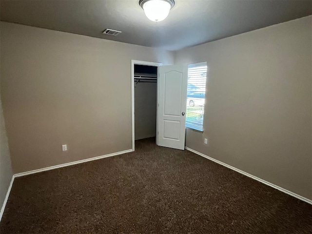 unfurnished bedroom with a closet and dark carpet