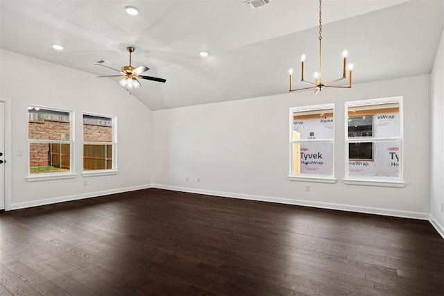 empty room featuring ceiling fan with notable chandelier, dark wood-type flooring, and vaulted ceiling