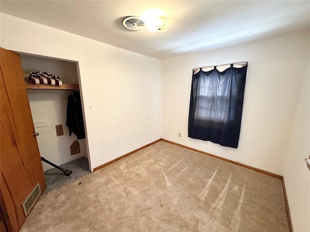 unfurnished bedroom with light colored carpet and a closet