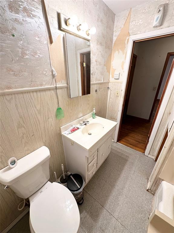 bathroom with wood walls, vanity, and toilet