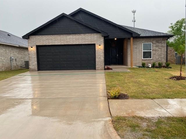 view of front of property featuring cooling unit, a garage, and a front lawn