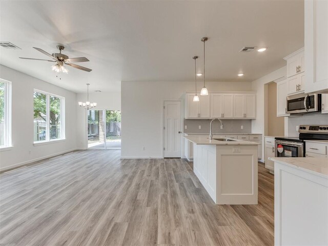 kitchen featuring light hardwood / wood-style floors, white cabinetry, stainless steel appliances, and hanging light fixtures