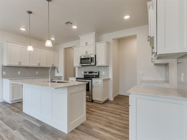 kitchen with stainless steel appliances, sink, pendant lighting, light hardwood / wood-style flooring, and white cabinets