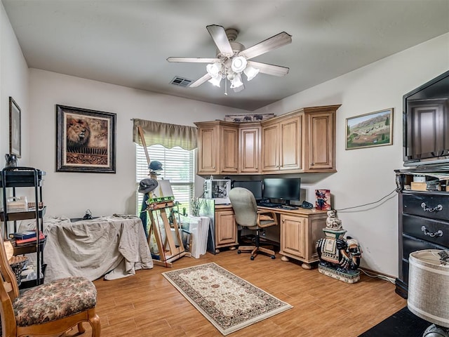 home office featuring ceiling fan, built in desk, and light hardwood / wood-style floors