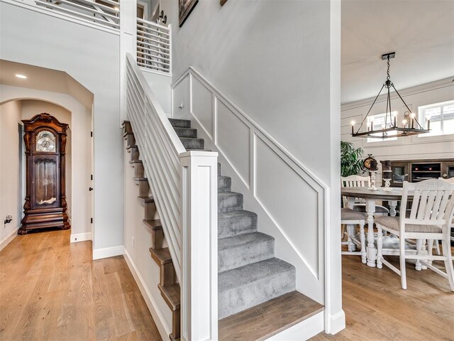 staircase with hardwood / wood-style flooring and a notable chandelier