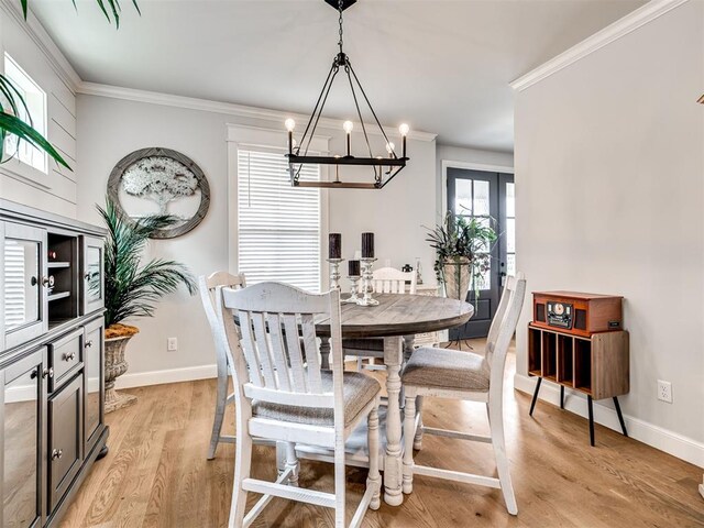 dining room featuring french doors, light hardwood / wood-style flooring, a notable chandelier, and ornamental molding