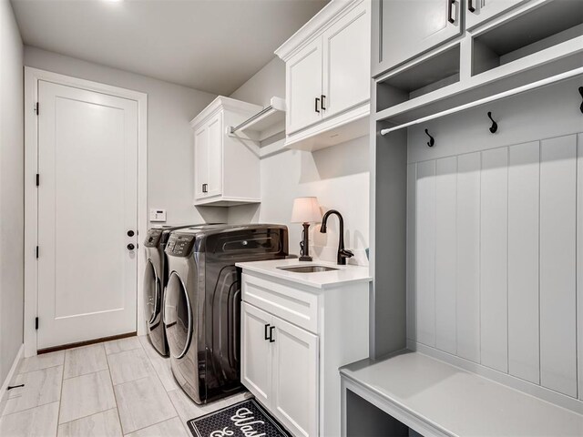 laundry room with cabinets, washer and clothes dryer, and sink