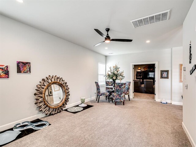 living area with light carpet and ceiling fan