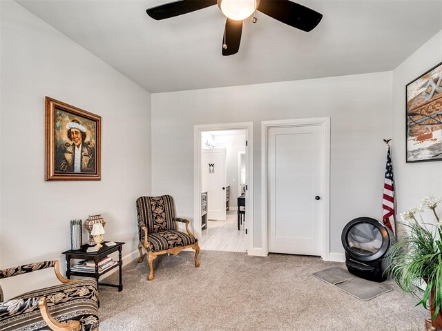 living area featuring light carpet and ceiling fan