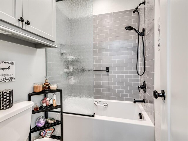 bathroom with tiled shower / bath combo and toilet